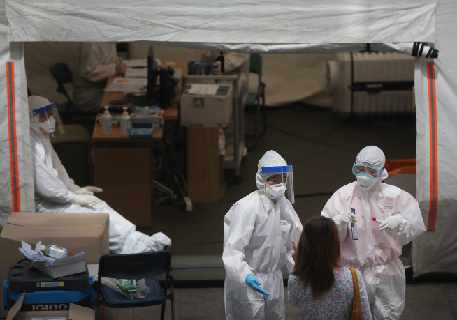 Medical workers carry out COVID-19 tests on visitors at a makeshift clinic in Seoul on May 18, 2020. (Yonhap)