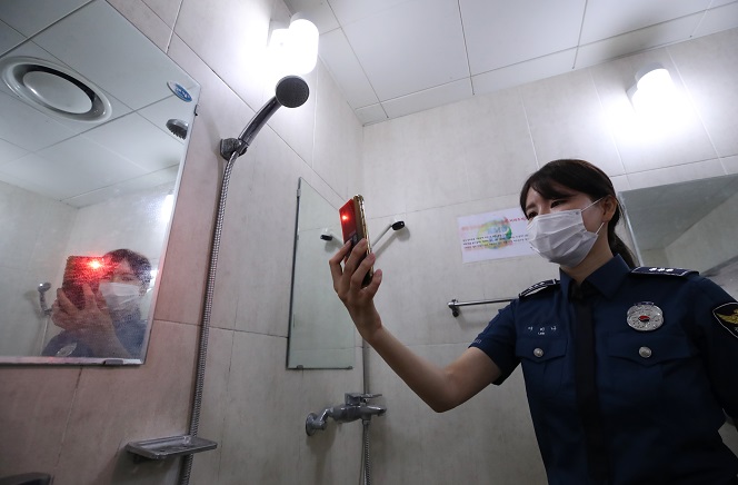 The police held demonstration on June 19, 2020 to detect illegal cameras hidden in a shower booth at Kookmin University’s Welfare Center by using a simple check card and a mobile phone. (Yonhap)