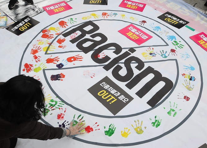 This March 18, 2018, photo shows a protester making a handprint during an anti-racism rally in Seoul. (Yonhap)
