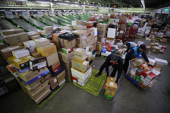 Workers at a logistics center affiliated with Korea Post in eastern Seoul sort deliveries on Jan. 14, 2020, ahead of the Lunar New Year holiday. (Yonhap)