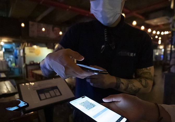 In the photo, taken June 10, 2020, a customer uses a QR code-based registration system to sign an entry log at a bar in Seoul. (Yonhap)