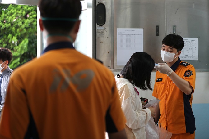 Test takers have their body temperatures checked before entering the venue of an exam for public servants in the southern port city of Busan on June 13, 2020. (Yonhap)