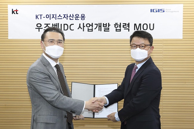 This photo provided by KT Corp. on June 17, 2020, shows Kim Youngwoo (R), head of KT's global business office, and Kang Young-goo, co-CEO of Igis Asset Management Ltd., posing for a photo after signing a partnership on internet data center business opportunities in Uzbekistan.