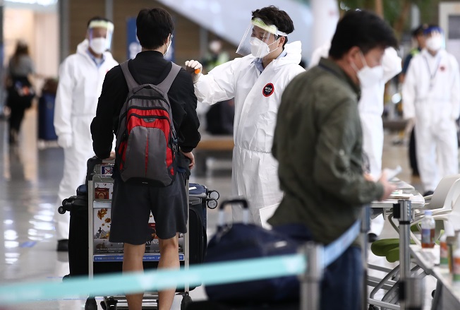 Quarantine officials check people arriving at Incheon International Airport on June 20, 2020. (Yonhap)