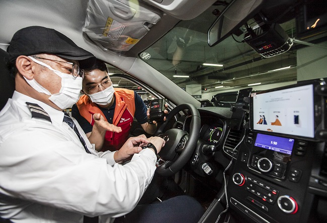 A SK Telecom Co. employee explains the advanced driver assistant system to a hearing-impaired taxi driver in this photo provided by SK Telecom on July 29, 2020.