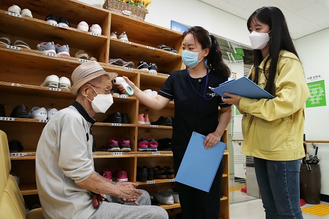 This photo, provided by the Seongdong Ward Office on June 12, 2020, shows health workers checking an elderly man's fever at a caregiving facility in the eastern Seoul ward.