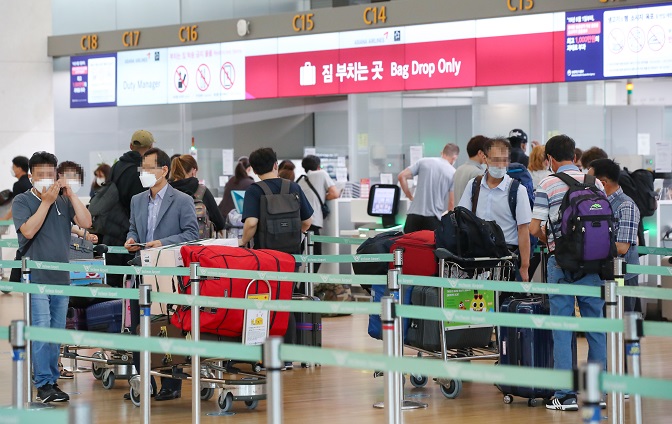 Travelers wait in a line to go through procedures for departure at Incheon International Airport, west of Seoul, on July 1, 2020. (Yonhap)
