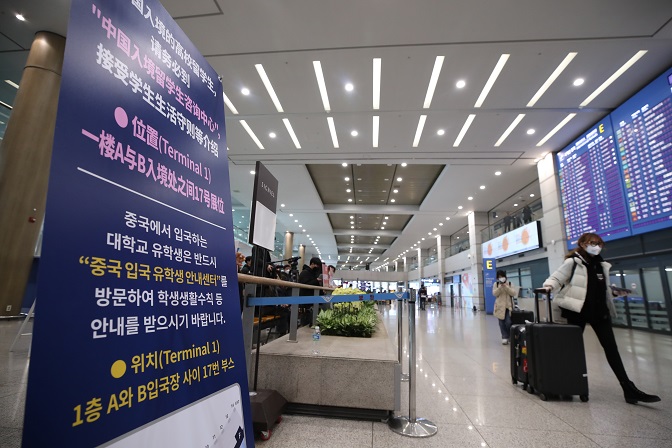 This file photo shows a foreign student walking past a public notice on quarantine procedures for international students at Incheon International Airport, west of Seoul. (Yonhap)