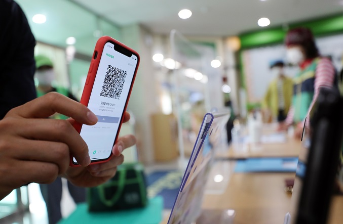 This file photo shows a person using a smartphone to scan a QR code before entering a public building. (Yonhap)