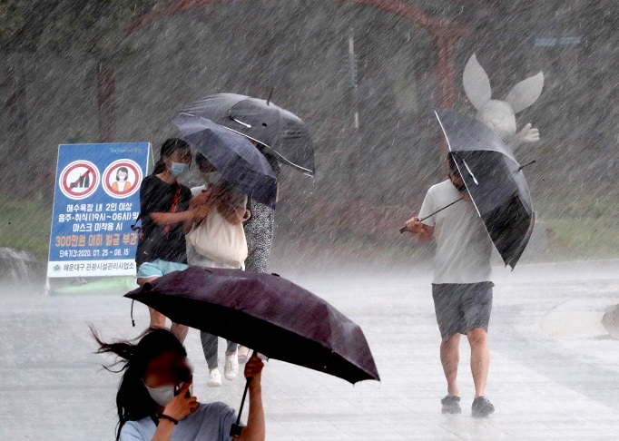 Pedestrians struggle to hold onto their umbrellas as heavy rain, accompanied by strong winds, poured in the southeastern port city of Busan on Aug. 10, 2020. (Yonhap)