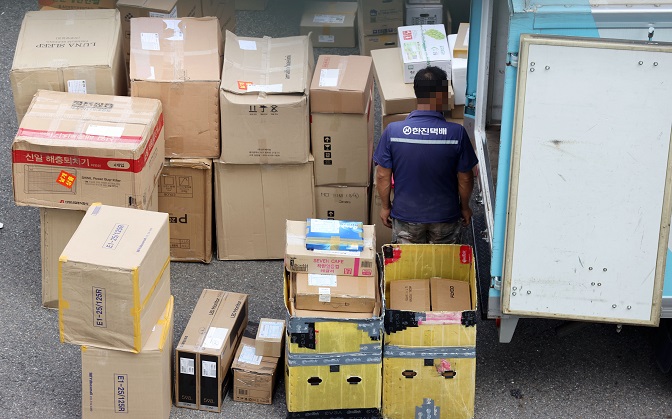 A delivery worker sorts through items that need to be delivered at a logistics center in Seoul on Aug. 13, 2020. (Yonhap)