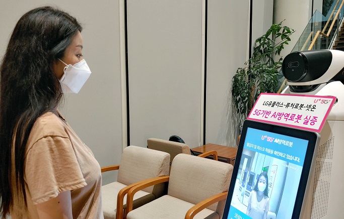 LG Uplus Corp.'s robot co-developed by robotics firm FutureRobot Co. and facial recognition technology developer Neton checks a model's temperature and whether she is properly wearing a mask in this photo provided by the company on Sept. 3, 2020.