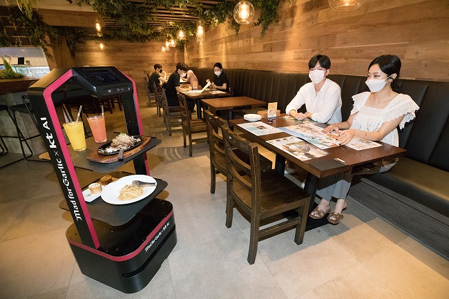 KT Corp.'s artificial intelligence-powered robot takes food and drinks to a table at a Mad for Garlic restaurant in southern Seoul, in this photo provided by the company on Sept. 1, 2020.