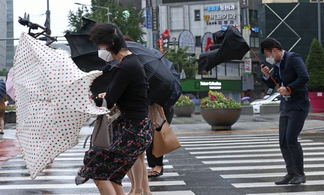 Commuters struggle to hold onto their umbrellas in central Seoul on Sept. 3, 2020. (Yonhap)