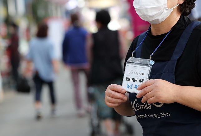 A shopkeeper at a traditional bazaar in Gwangju, 330 kilometers south of Seoul, wears a sign informing customers that she has tested negative for the new coronavirus on Sept. 12, 2020, after the market was closed for two days due to COVID-19 cases reported nearby. (Yonhap)
