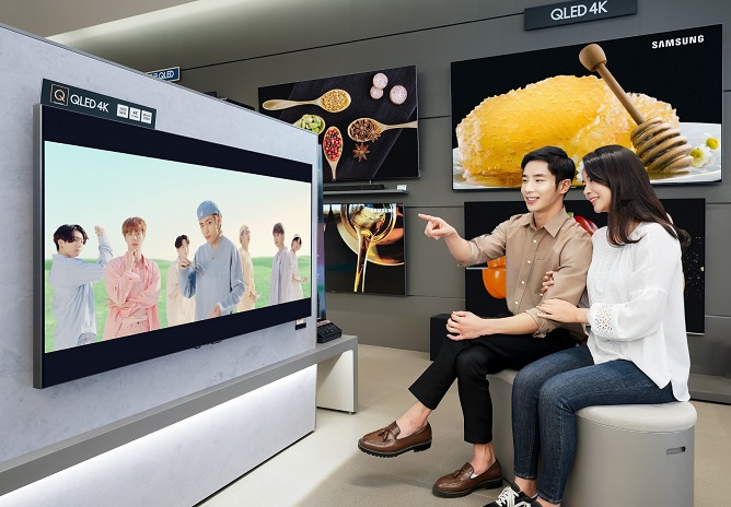 This photo provided by Samsung Electronics Co. on Oct. 8, 2020, shows models watching the music video of "Dynamite," K-pop sensation BTS' latest single, on Samsung's QLED TV.