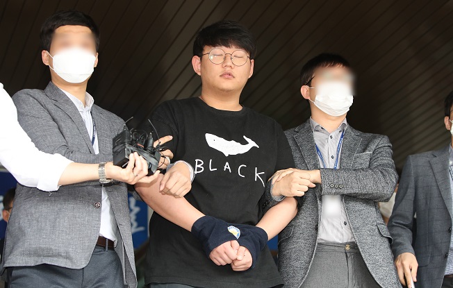 Moon Hyung-wook (C), a 24-year-old alleged mastermind of a high-profile digital sexual exploitation ring, appears before the press at the Andong Police Station in Andong, 270 kilometers southeast of Seoul, on May 18, 2020. (Yonhap)