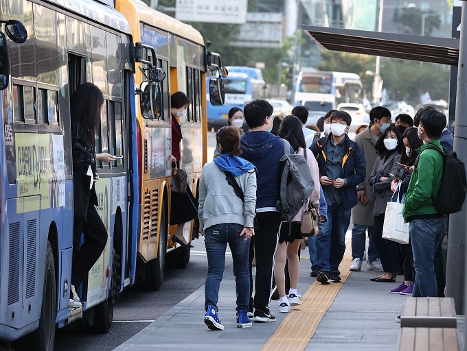 Commuters wearing protective masks wait for buses in central Seoul on Oct. 5, 2020. (Yonhap)