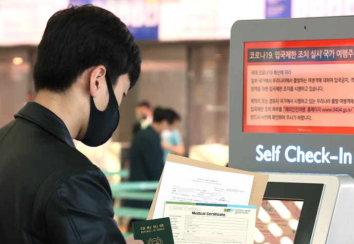 A traveler shows a medical certificate verifying his negative COVID-19 test at a check-in counter in Incheon International Airport, west of Seoul, on Oct. 8, 2020, when South Korea and Japan put into practice an agreement on the fast-track entry of businesspeople without a two-week coronavirus quarantine amid the pandemic. (Yonhap)