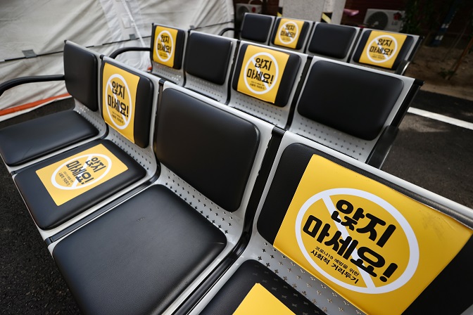 Signs on seats next to a COVID-19 screening center at the National Medical Center in Seoul inform visitors to maintain social distancing on Oct. 11, 2020. (Yonhap)