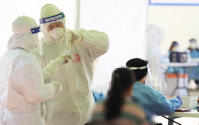 Medical workers carry out new coronavirus tests on visitors at a makeshift clinic in Siheung, southwest of Seoul, on Oct. 20, 2020. (Yonhap)