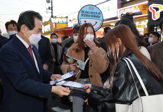 Prime Minister Chung Sye-kyun (L) hands out face masks to citizens during an antivirus campaign in the Hongdae district of Seoul on Nov. 7, 2020. (Yonhap)