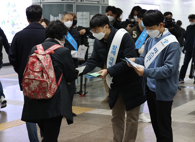 Seoul city and Seoul Metro officials hand out fliers explaining the enforcement of a new law that will fine people who are not wearing a face mask, at Gwanghwamun Station in downtown Seoul on Nov. 13, 2020. (Yonhap)