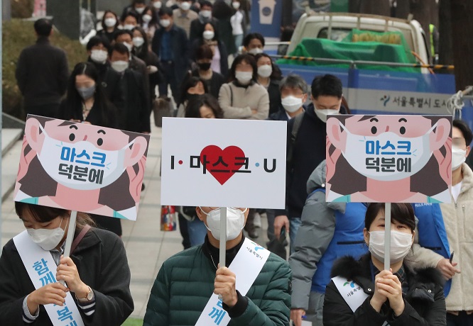 Seoul city officials carry signs urging citizens to wear a face mask in downtown Seoul on Nov. 13, 2020. (Yonhap)