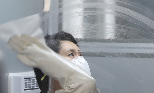 A medical worker at the National Medical Center cleans the glass of a screening station for COVID-19 on Nov. 17, 2020. (Yonhap)