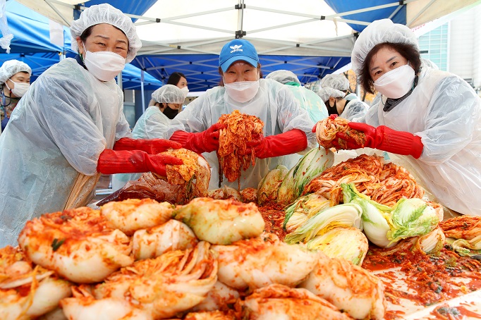 A group of volunteers poses with kimchi, a traditional Korean side dish normally made of fermented cabbage, salt and hot peppers, during an event held in eastern Seoul on Nov. 18, 2020, in this photo released by the Seongdong Ward.