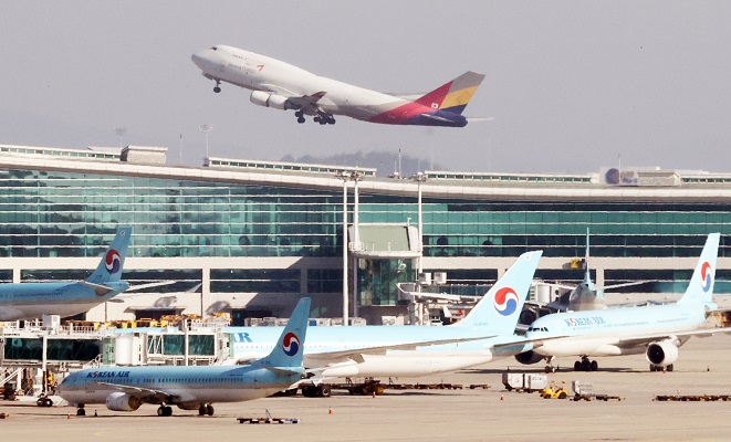 This photo taken on Dec. 1, 2020, shows an Asiana passenger jet taking off from the Incheon International Airport against the background of Korean Air planes in Incheon, just west of Seoul. (Yonhap)