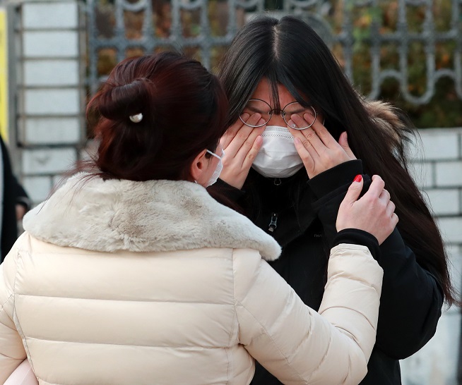 A student taking the College Scholastic Ability Test cries as she parts with her mother outside a high school in Busan, 453 kilometers southeast of Seoul, on Dec. 3, 2020. (Yonhap)
