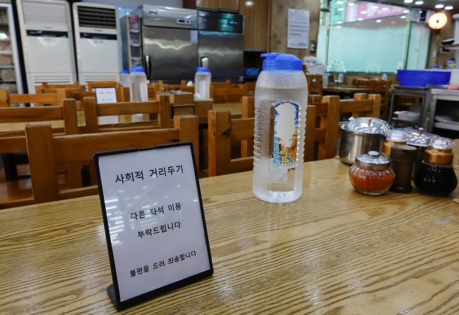 A sign at a Seoul restaurant on Dec. 22, 2020, asks customers to sit at a different table to maintain a social distance. (Yonhap)