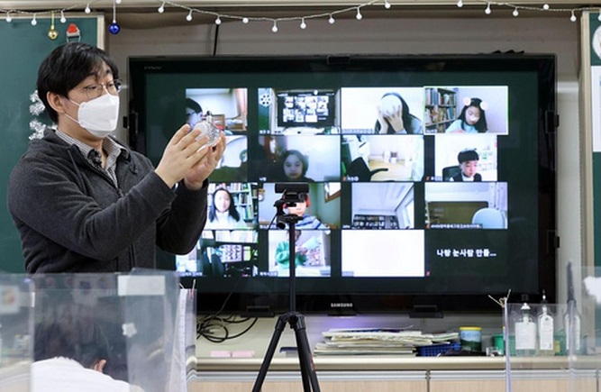In the Dec. 14, 2020, file photo, a screen behind a teacher shows students taking an online class at Hwarang Elementary School in Seoul on Dec. 14, 2020. (Yonhap)