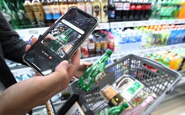 In this photo taken on Aug. 17, 2018, a customer scans the bar code of a product using retail giant Shinsegae's mobile app at its cashier-less store in Seoul. (Yonhap)