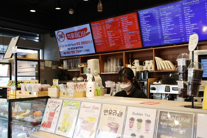 This file photo shows a sign (top left) criticizing the government's COVID-19 business restrictions at a cafe in southern Seoul on Jan. 6, 2021. (Yonhap)