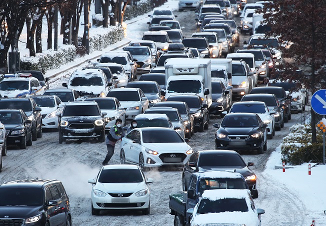 Cars move slowly on a snow-covered road in Suwon, just south of Seoul, on Jan. 7, 2021. (Yonhap)