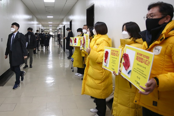 Justice Party lawmakers stage a sit-in in front of the meeting room of the parliamentary Legislation and Judiciary Committee's subcommittee in charge of legislation review on Jan. 7, 2021, in protest of a diluted legislation bill on preventing severe workplace disasters. (Yonhap)