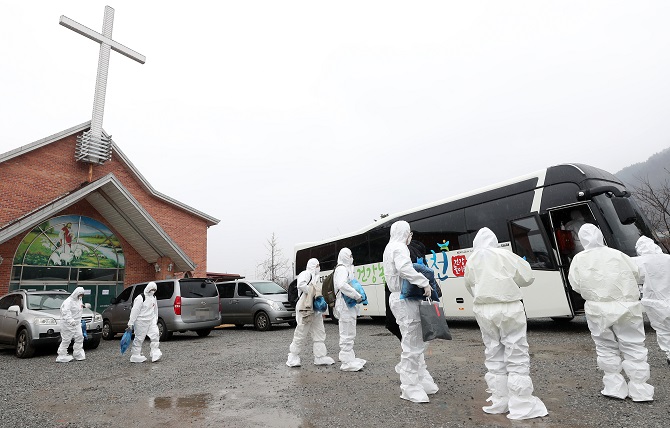 IEM School students and instructors, who tested positive for COVID-19 while attending a winter retreat at a church in Hongcheon, southeast of Seoul, prepare to board a bus bound for a residential treatment center on Jan. 26, 2021. (Yonhap)