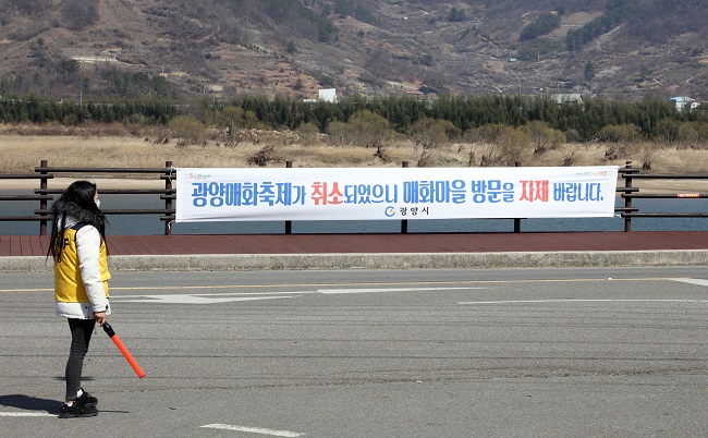 This file photo taken on March 6, 2020, shows a Gwangyang city official standing at the entrance of a public parking lot near the venue of the Gwangyang International Maehwa Festival in southwestern South Korea to turn away visitors after the festival was canceled due to COVID-19. (Yonhap) 