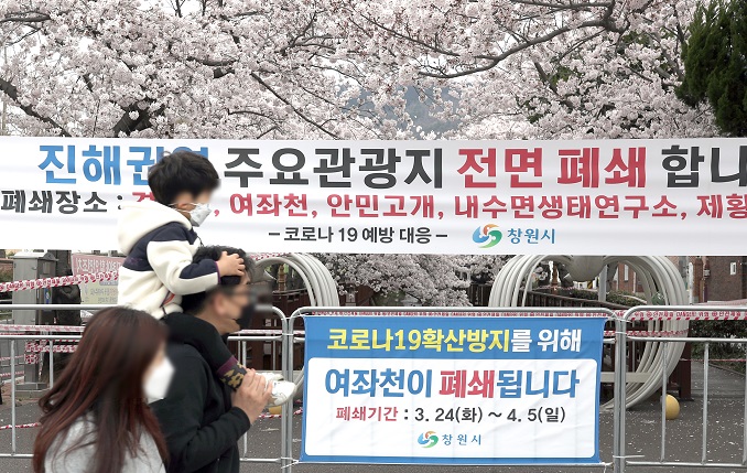 Citizens pass by a banner announcing the cancellation of the Jinhae Gunhangje Festival in Changwon, southeastern South Korea, in this file photo taken on March 29, 2020. (Yonhap)