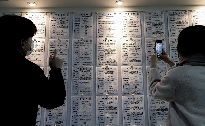 This file photo, taken Jan. 13, 2021, shows people looking at job opening information at an employment arrangement center in Seoul. (Yonhap)