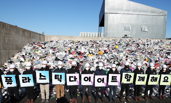 In this file photo taken on Jan. 19, 2021, officials of Suwon Urban Development Corp. hold up signboards that read, "Let's go on a plastic diet," at a recycling center in Suwon, just south of Seoul. (Yonhap)