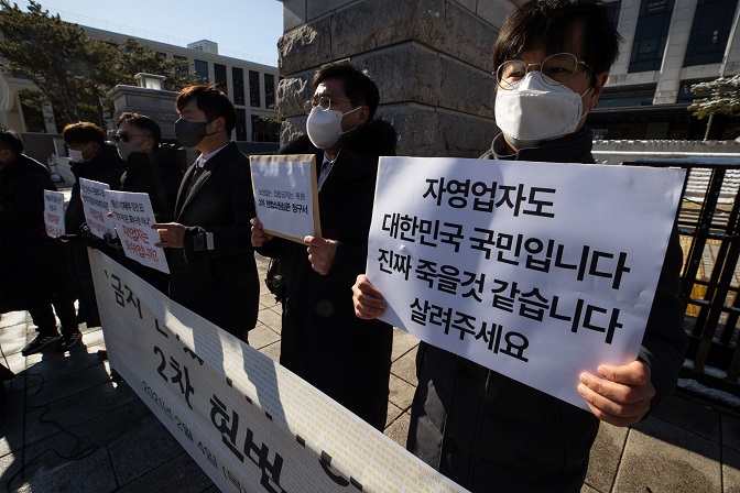 Associations of small businesses hold a press conference in front of the Constitutional Court, asking it to review whether virus-related restrictions violate their basic property rights, in Seoul on Feb. 4, 2021. (Yonhap)