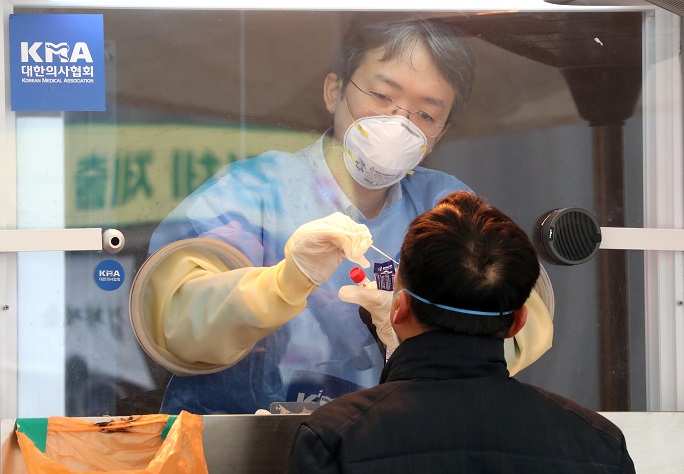 A medical worker conducts a virus test on a man at a makeshift testing booth in front of Seoul Station on Feb. 5, 2021. (Yonhap) 