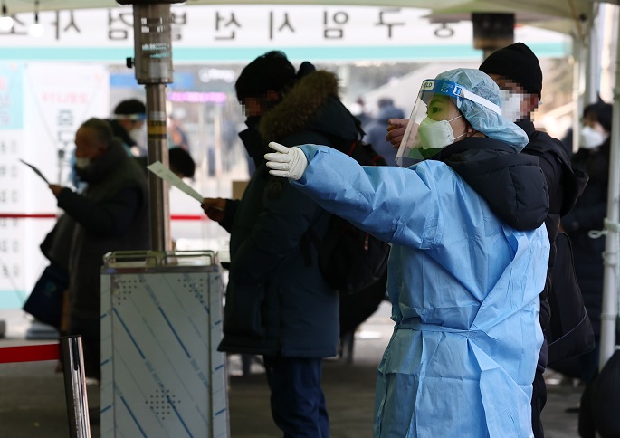 A health worker clad in protective gear gives directions to a citizen at a makeshift virus testing clinic in Seoul on Feb. 12, 2021. (Yonhap)