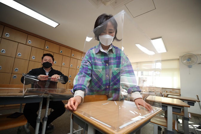 Teachers set up plastic partitions at a classroom in Daegu, 302 kilometers south of Seoul, on Feb. 23, 2021. (Yonhap)