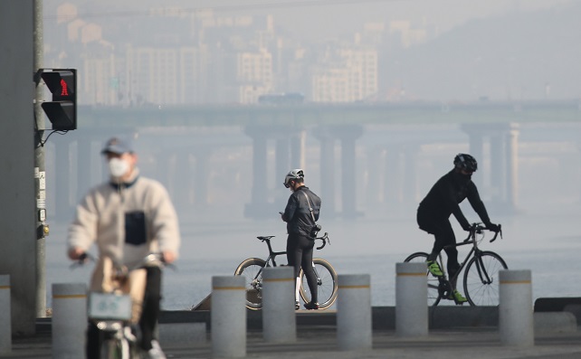 This file photo, taken Feb. 21, 2021, shows citizens riding bikes at a riverside park in southern Seoul, with the capital gripped by fine dust and fog. (Yonhap)