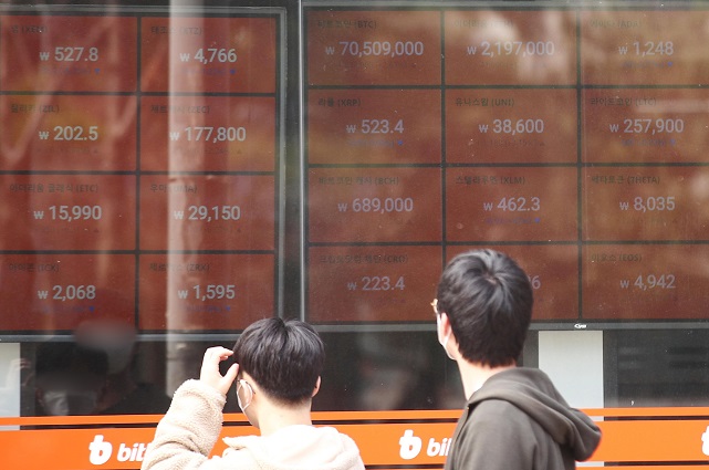 Investors look at the electronic board of a cryptocurrency exchange in Seoul on March 14, 2021, with the price of bitcoin surpassing 71 million won per unit at one time during the session. (Yonhap)