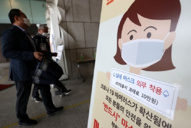 A standing signboard is set up at the entrance of an office building in downtown Seoul on April 12, 2021, to publicize mandatory mask wearing in all indoor public places. (Yonhap)